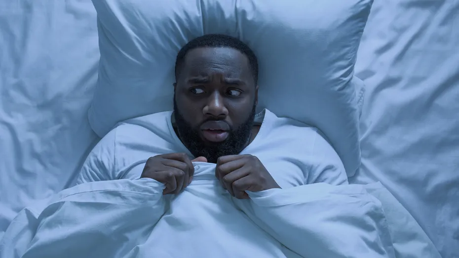 Man laying on a bed scared