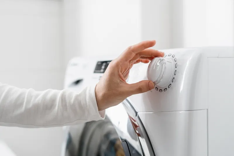cropped shot of woman hand turn on automatic washing machine