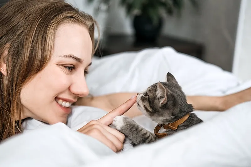 woman smiling in front of adopted kitten