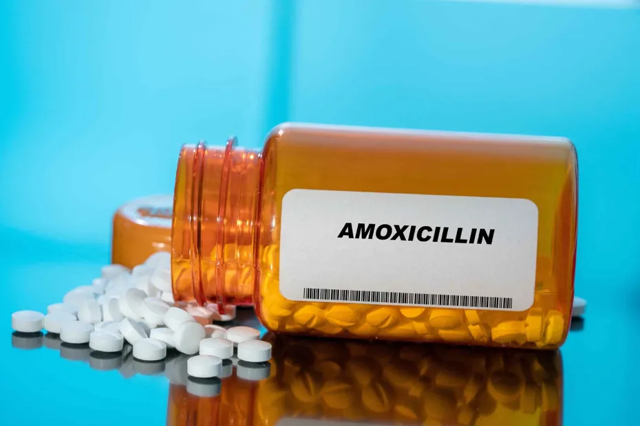 Amoxicillin white medical pills and tablets spilling out of a drug bottle
