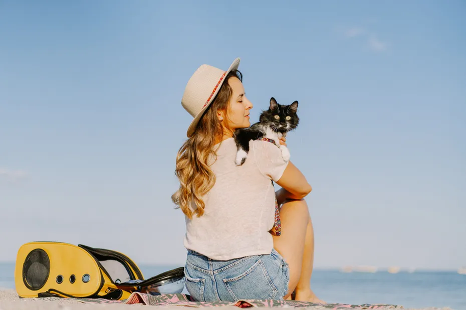 Young woman with a cat and backpack near the beach