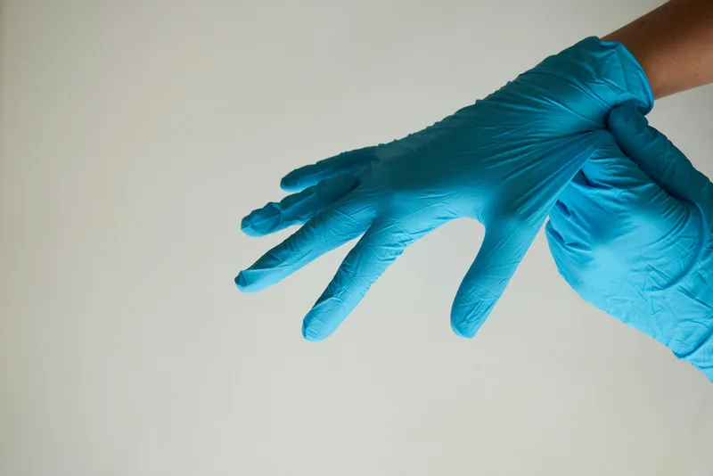 persons hand with blue rubber gloves