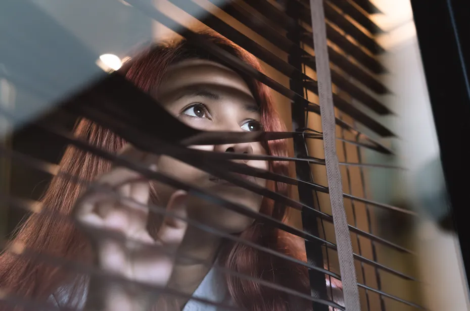 Scared woman staring outside a window