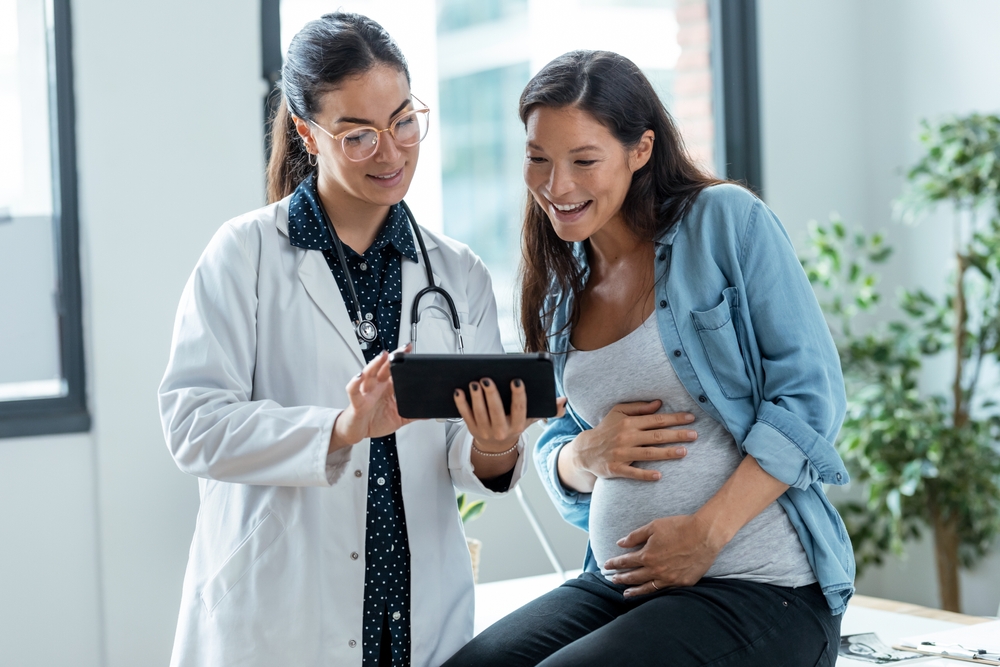 female gynecologist doctor showing to pregnant woman ultrasound scan baby with digital tablet