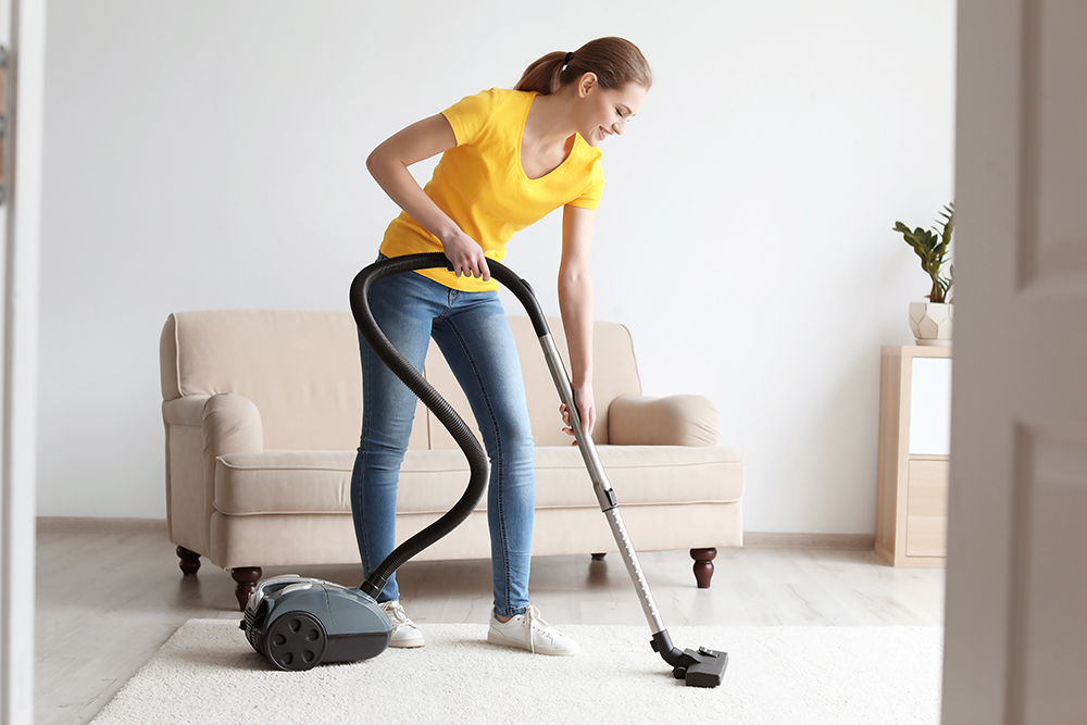 young woman vacuuming the carpet