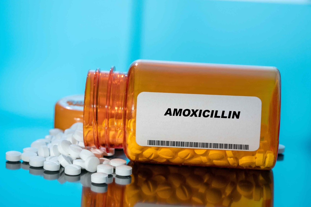 Amoxicillin white medical pills and tablets spilling out of a drug bottle