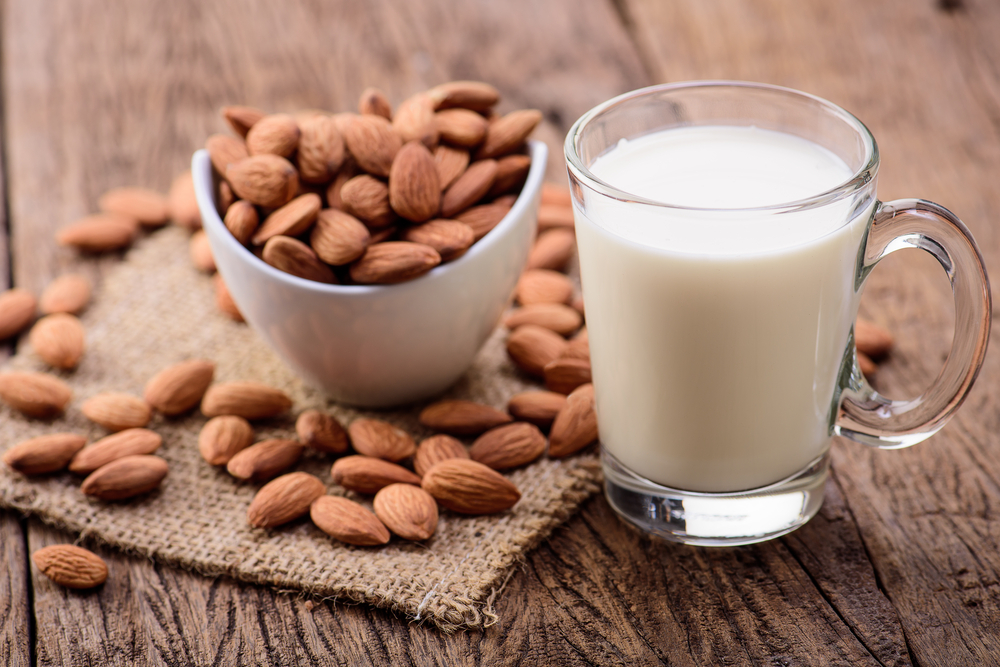 almond milk in glass with almonds on the side