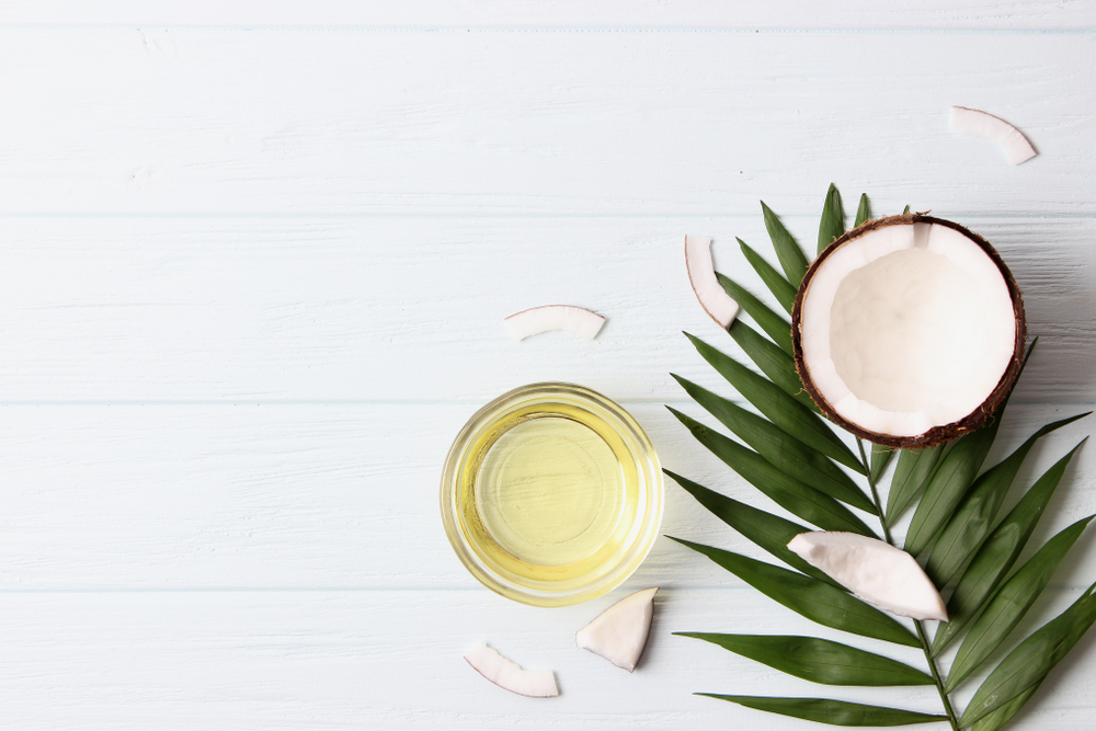 coconut oil, coconuts and green tropical leaves
