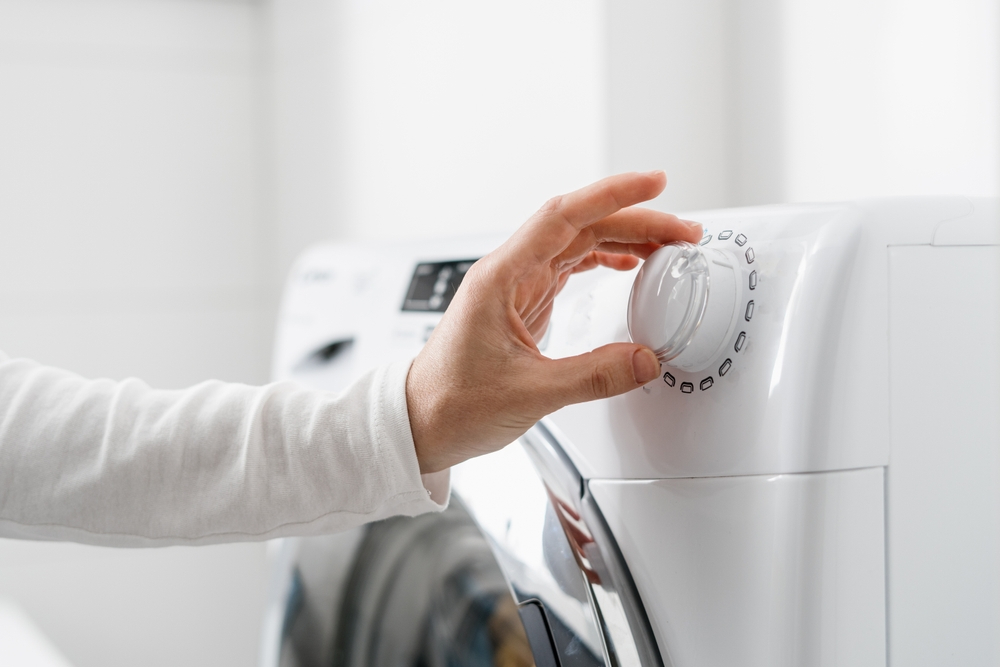 cropped shot of woman hand turn on automatic washing machine