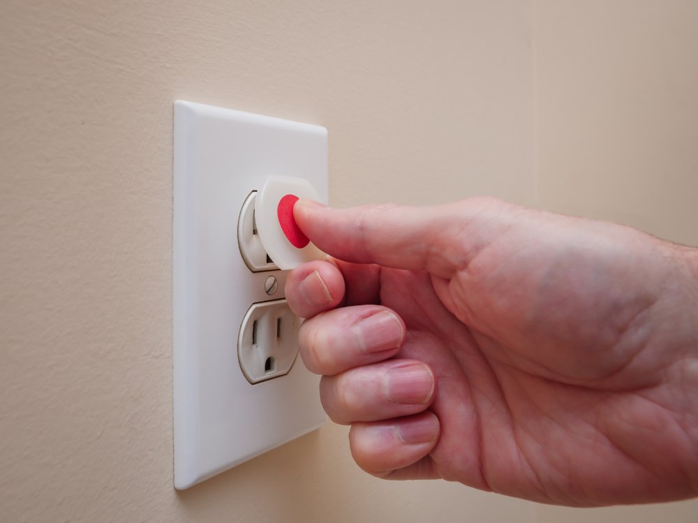 hand putting safety plugs on outlet