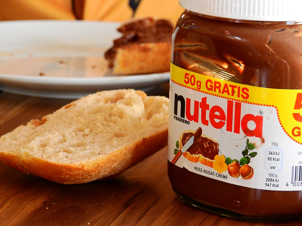 jar of nutella beside a slice of bread